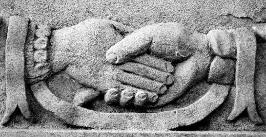 cnmonument two hands shaking on a gravestone