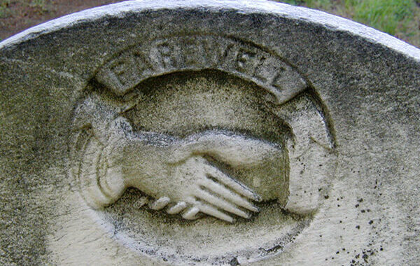 two hands shaking on a gravestone